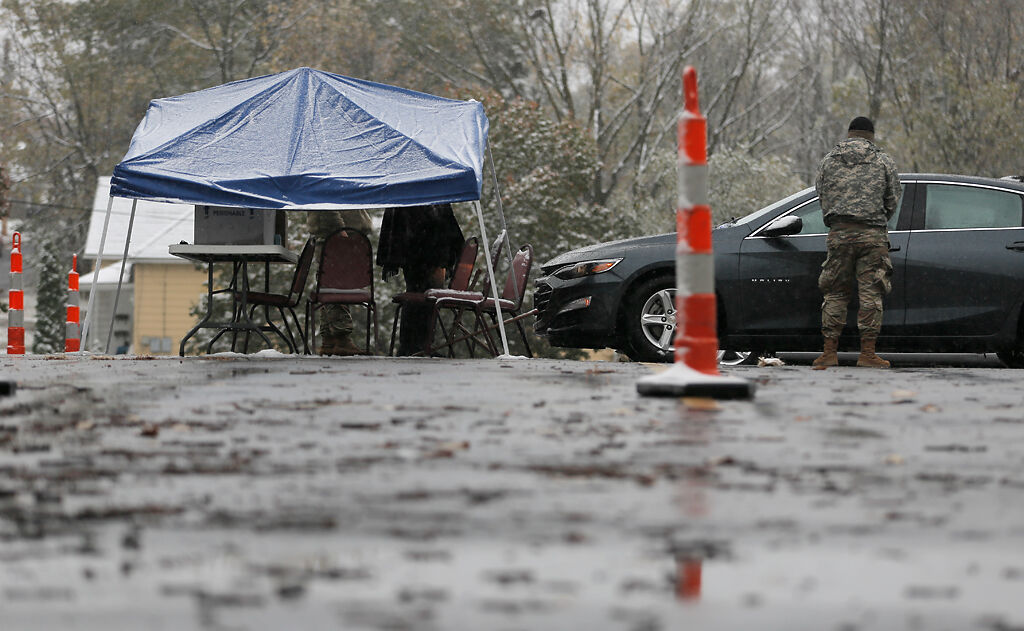 A National Guardsman stands watch as medical workers give COVID-19 tests during a snow storm on Monday in Columbia.